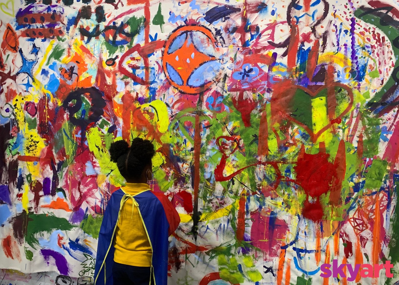 a small black girl stares at a colorful abstract painting