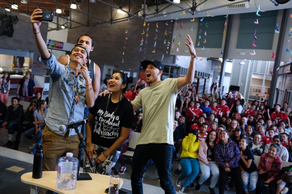 four artists on stage take a selfie with their young audience