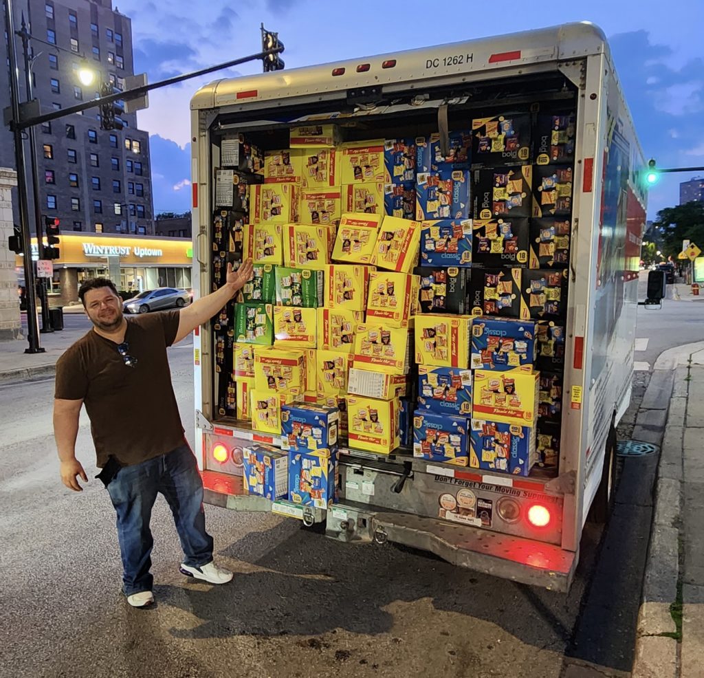 Mustafa showing off a a truck filled to the brim with chips, picked up for our food rescue partners.