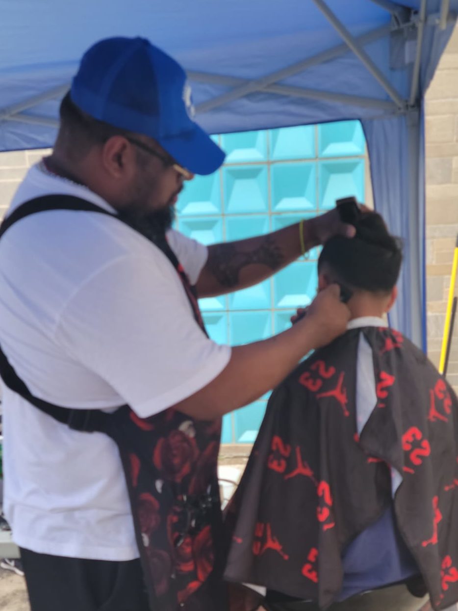 An Onward House partner giving a haircut to a young child.