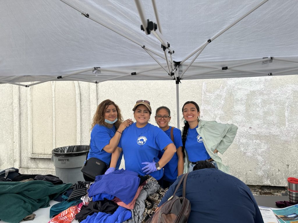 Onward House members smiling at the clothes table.