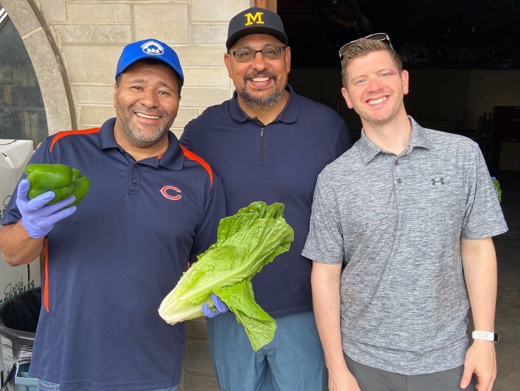 Onward House members smiling and holding produce.