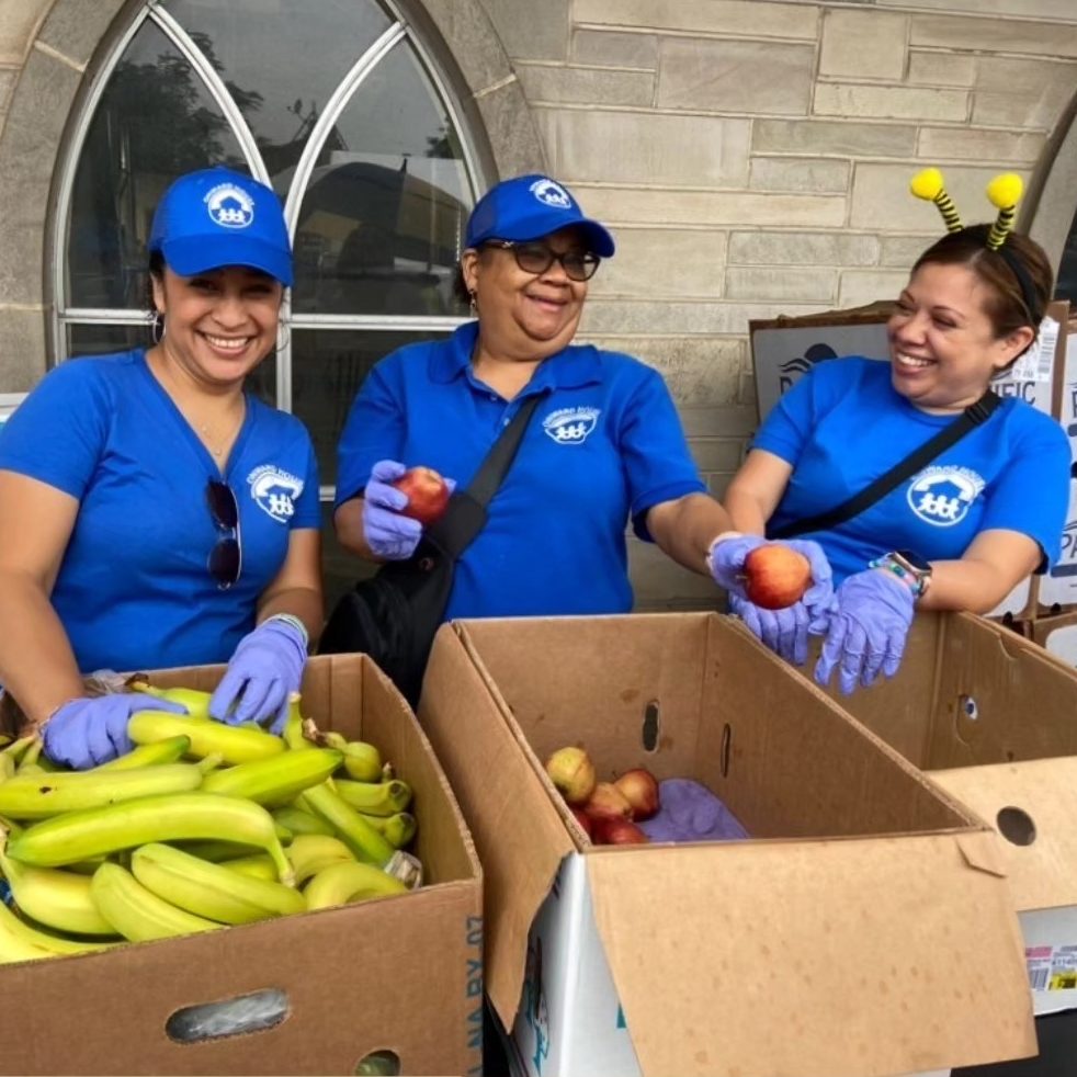 Members of Onward House smiling, laughing, and passing out produce