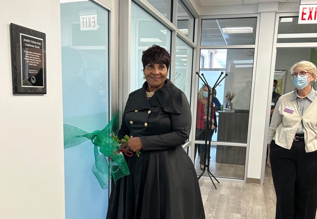 Jennifer Nelson-Seals, former Interfaith House & The Boulevard CEO, cuts the green ribbon on the door of the new conference room.