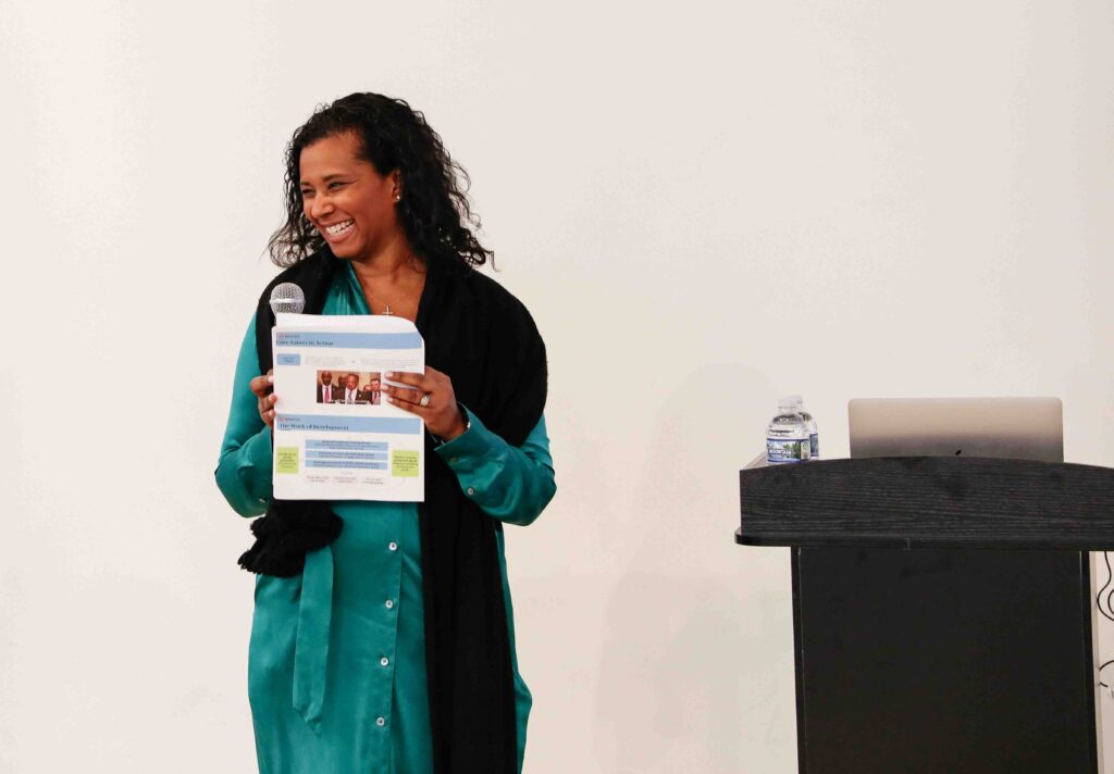 Aimée Eubanks Davis smiles in front of a podium at the Leaders of Color Collective event.